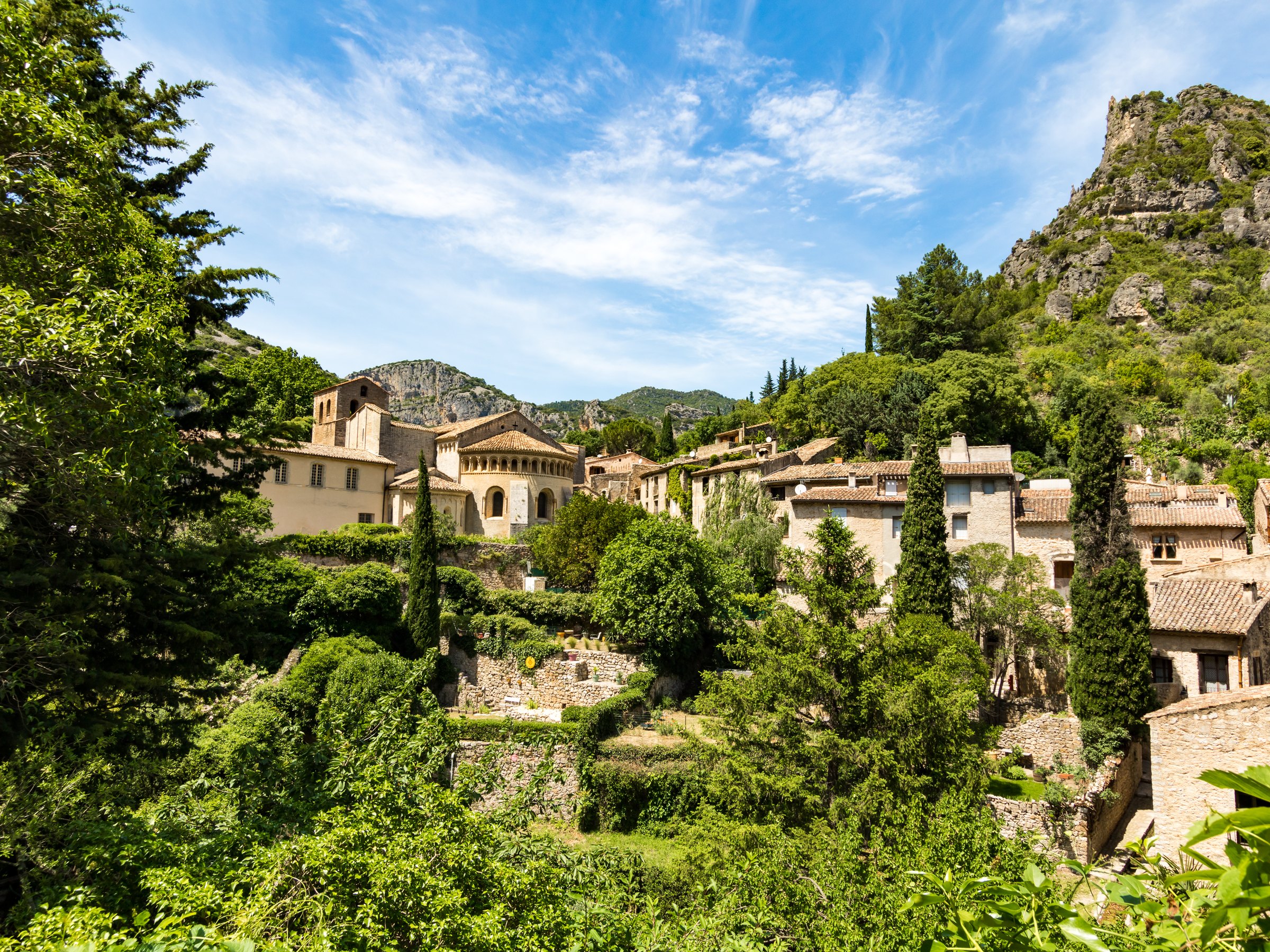 The village of Saint-Guilhem-le-Désert among the greenery, below the cliffs
