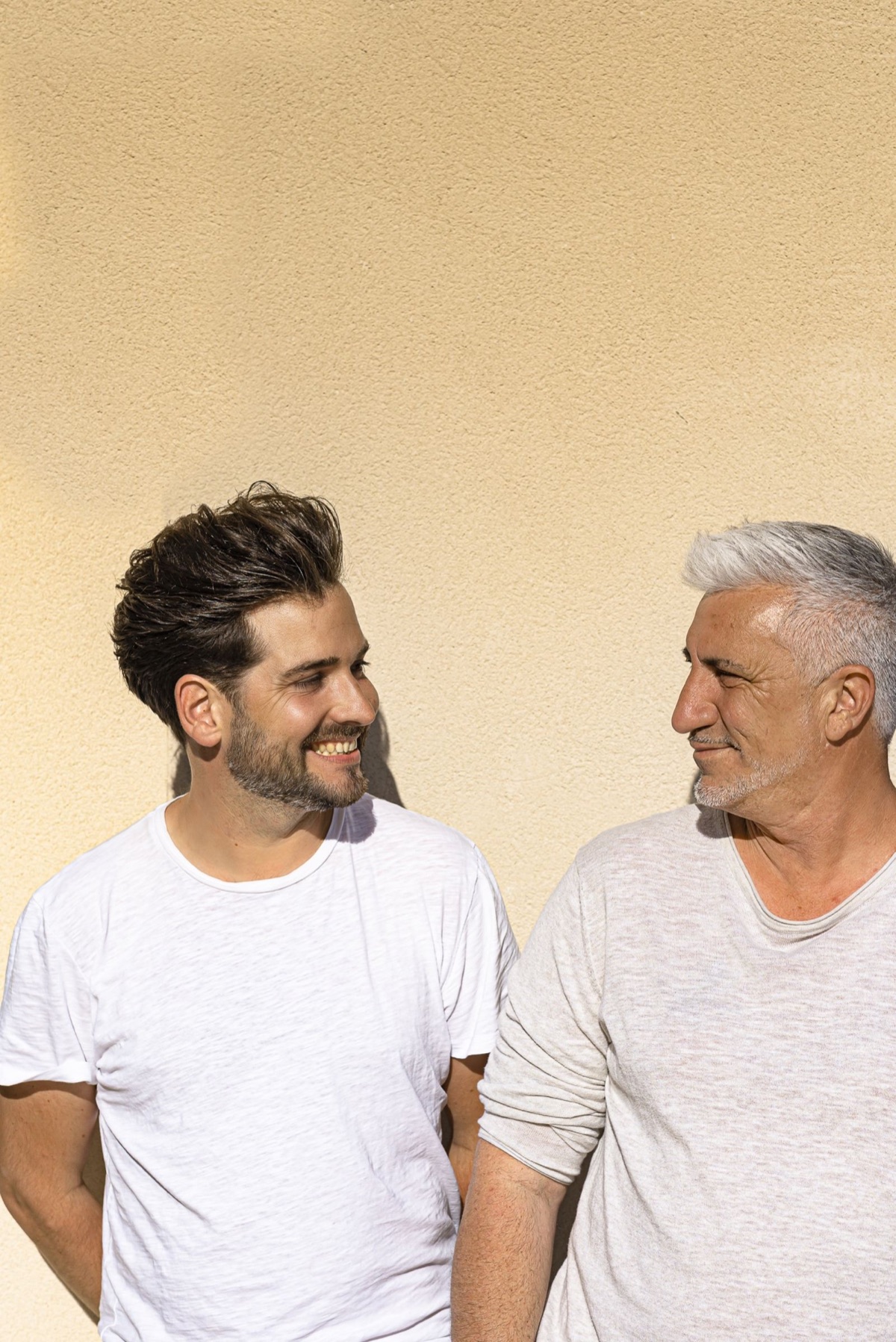 Gilles and Fabien exchange a knowing look in front of an ocher wall