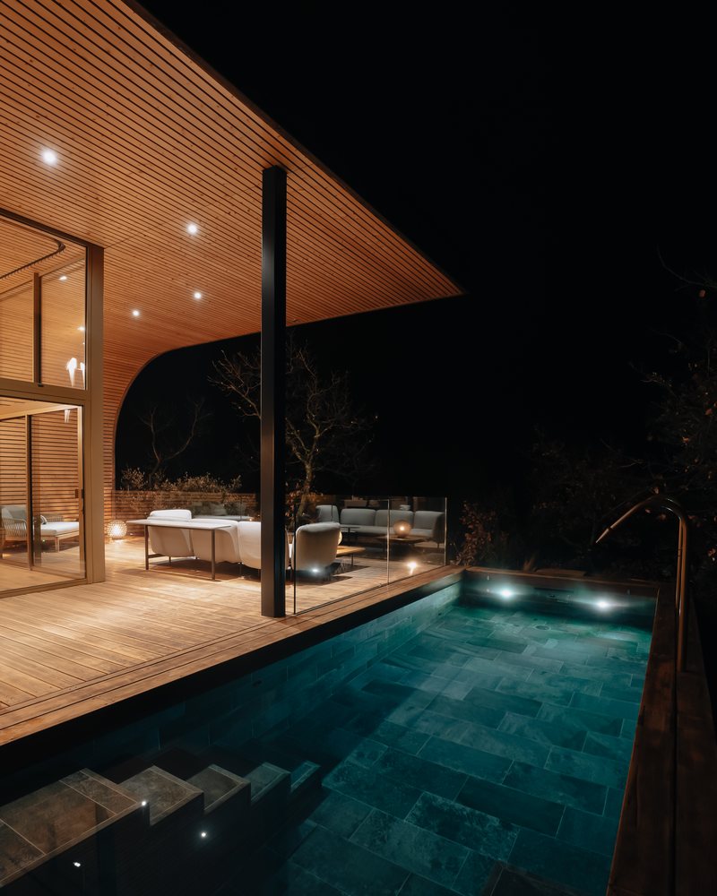 La piscine privée d’un lodge, éclairée de nuit et chauffée à 32 °C, entourée d’arbres nus