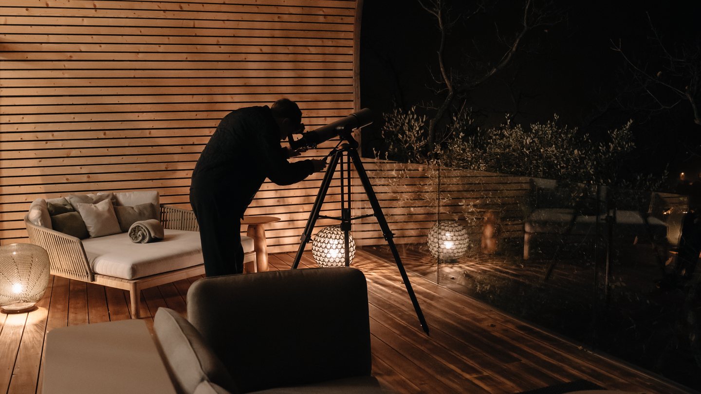 Un voyageur observe le ciel depuis la terrasse du lodge, de nuit