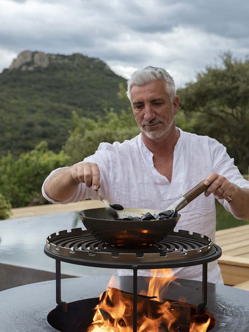 Gilles at the brazier: he turns mussels in a pan placed on the flames, the Pic at the bottom